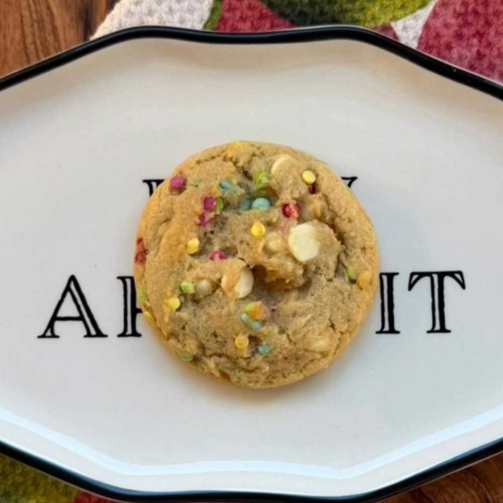 A Birthday Cake cookie with colorful sprinkles and white chocolate chips on a white platter
