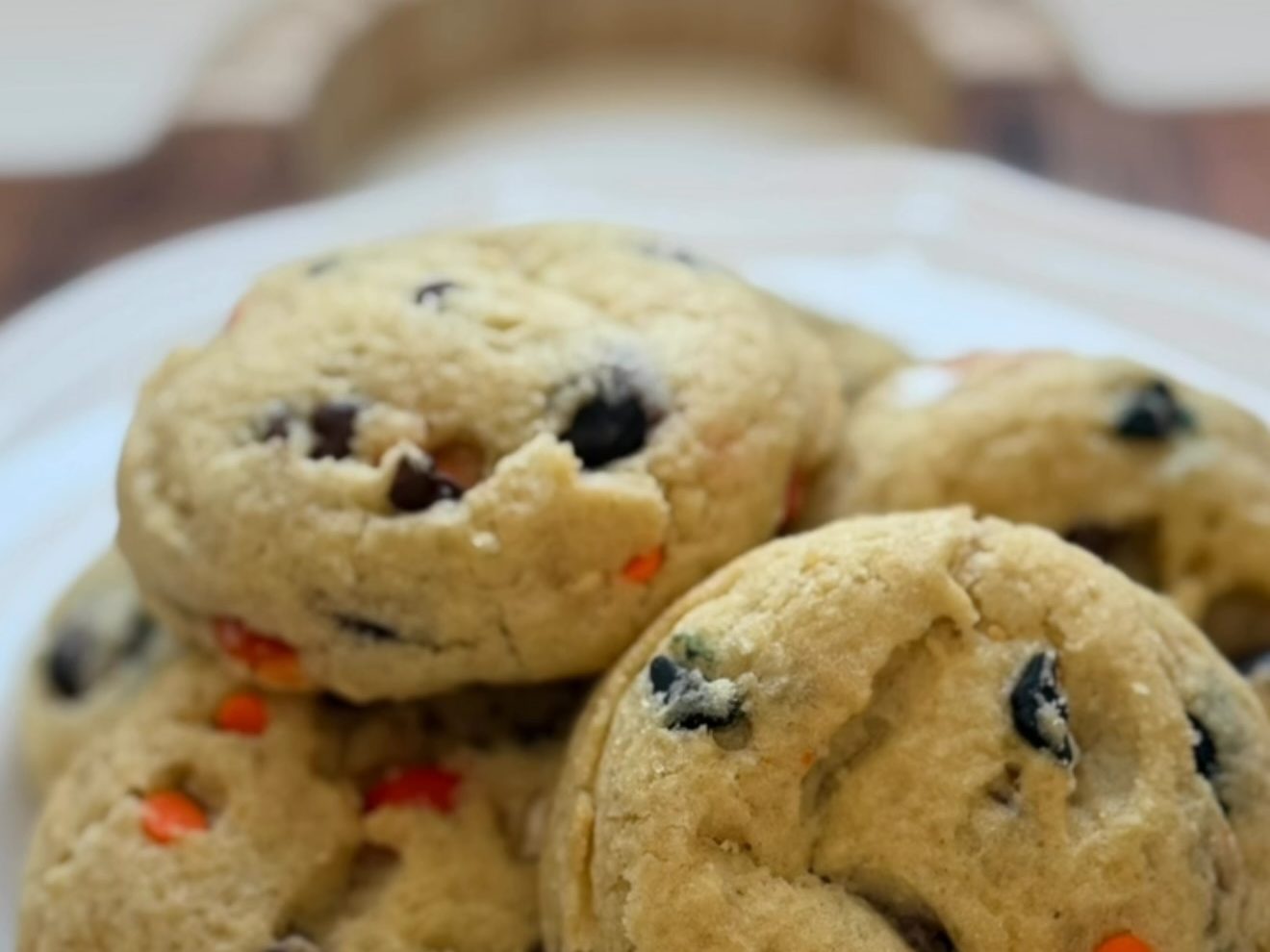 Soft homemade Friendly Goose cookies with orange, brown, and black candy pieces piled on a white plate